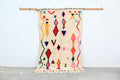 Handmade beige azilal rug with colorful geometric patterns bedroom