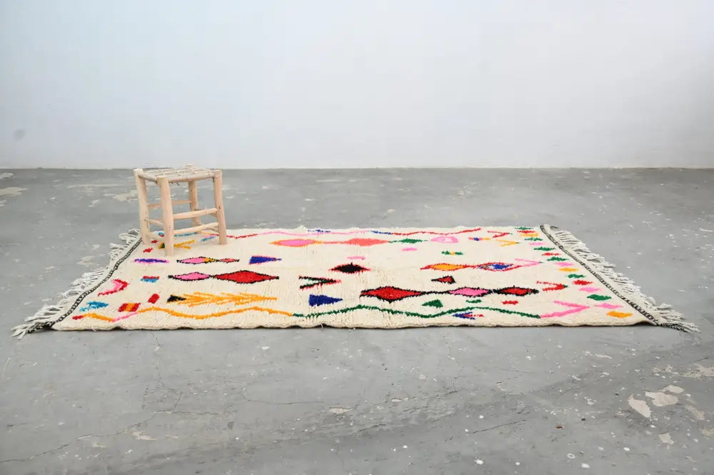 Handmade beige azilal rug with colorful geometric patterns bedroom
