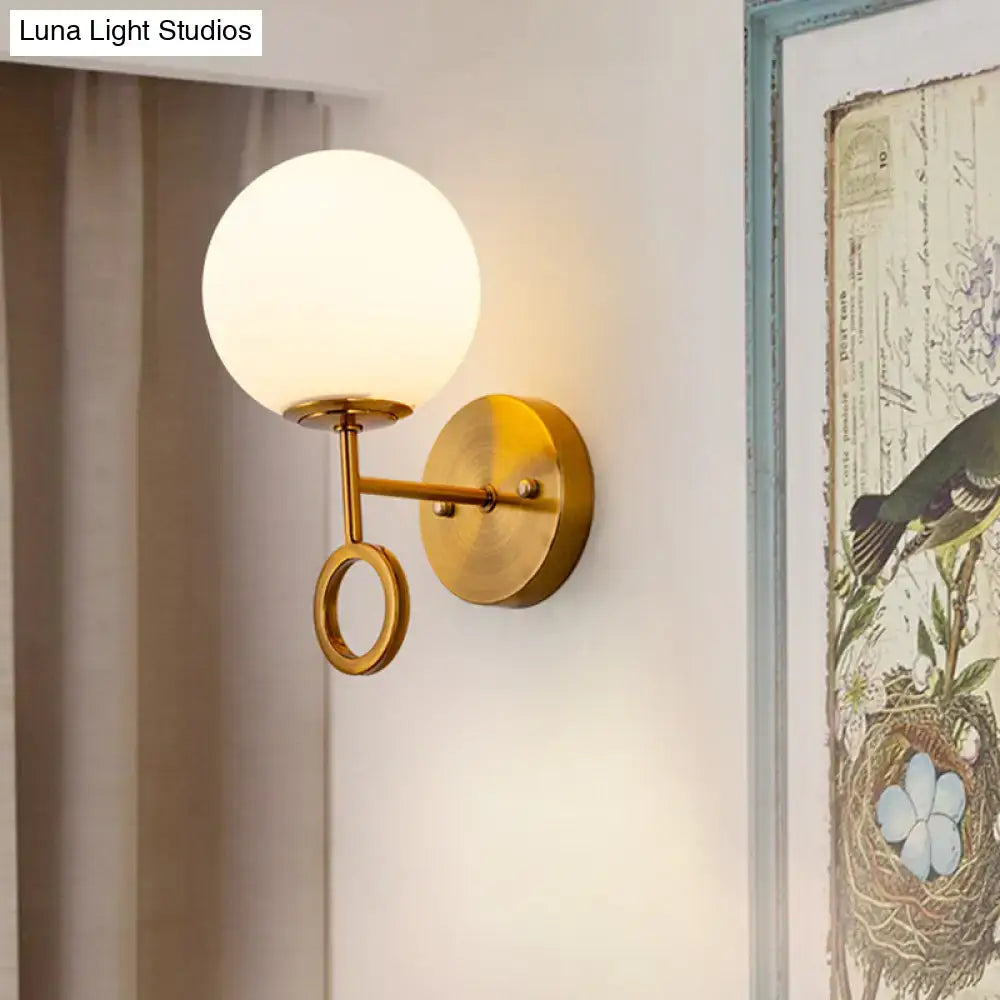 Minimalist brass wall sconce with cream glass shade bedroom light