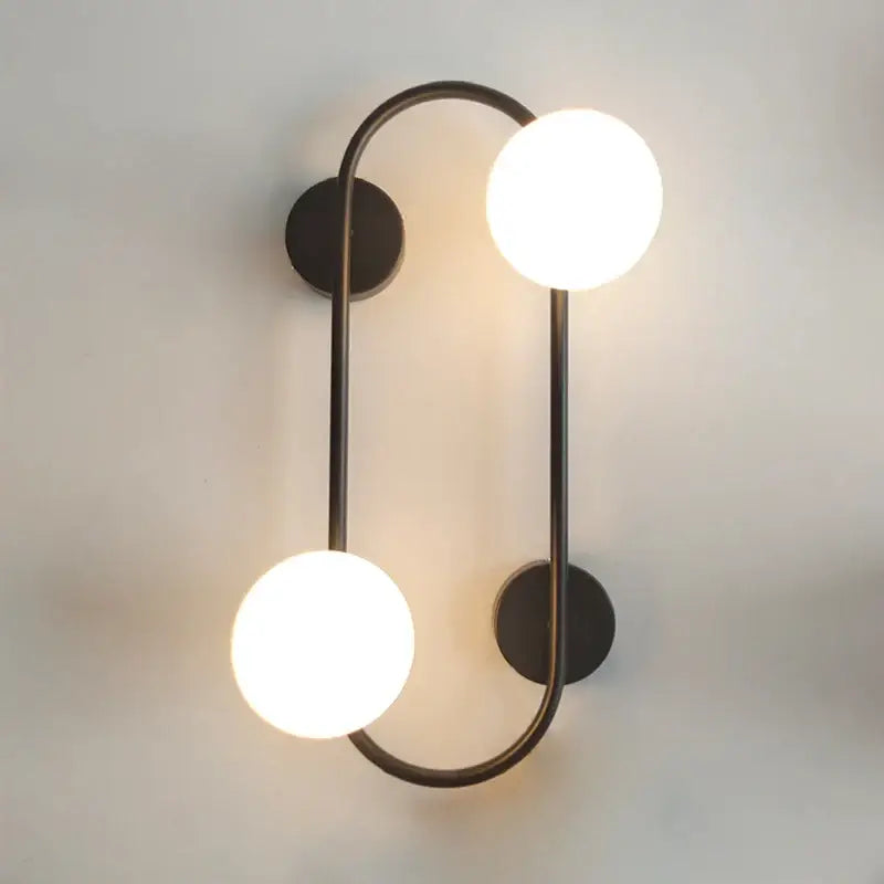 Modern black wall sconce with frosted glass globes – bedroom light