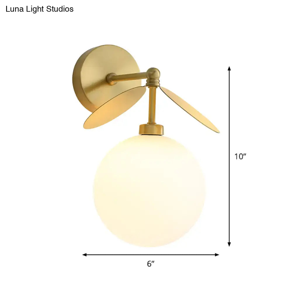 Modern brass leaf wall lamp with cream glass bedroom sconce